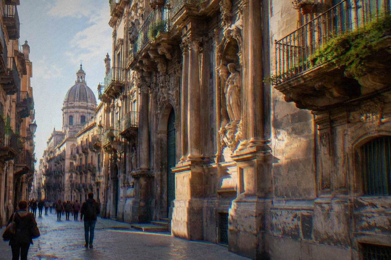A sunlit Palermo street with ornate baroque buildings and pedestrians walking under balconies