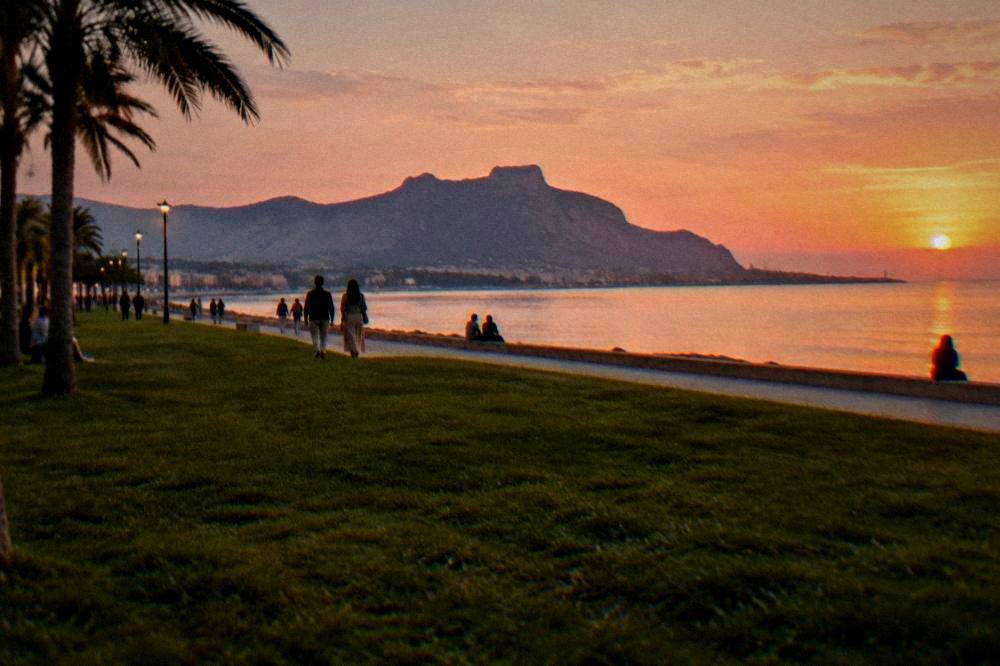 People strolling on the Foro Italico seafront lawn in Palermo in warm evening light