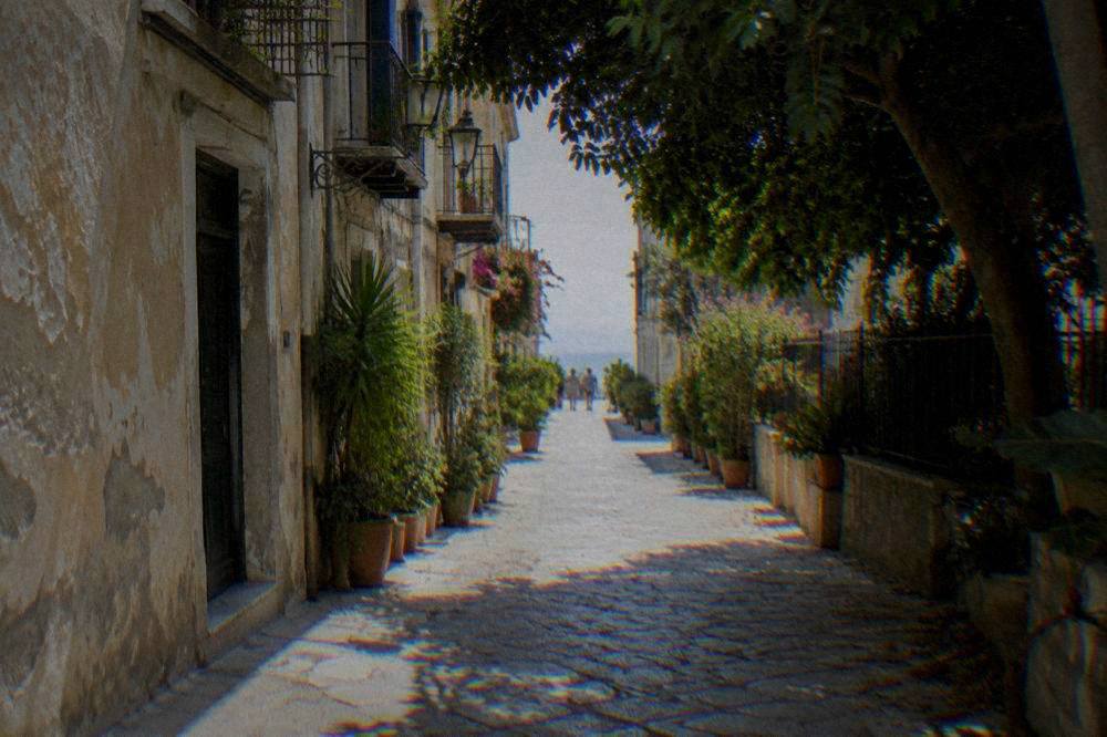 A stone lane in the Kalsa district of Palermo with old plastered walls and potted plants