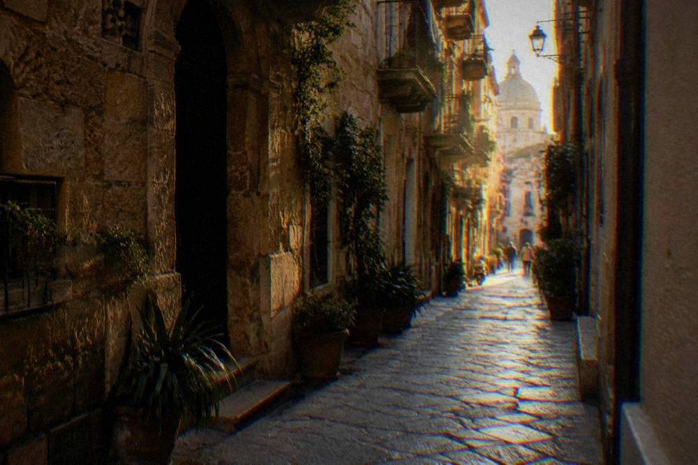 A shady narrow street in the old centre of Palermo with sun at the far end