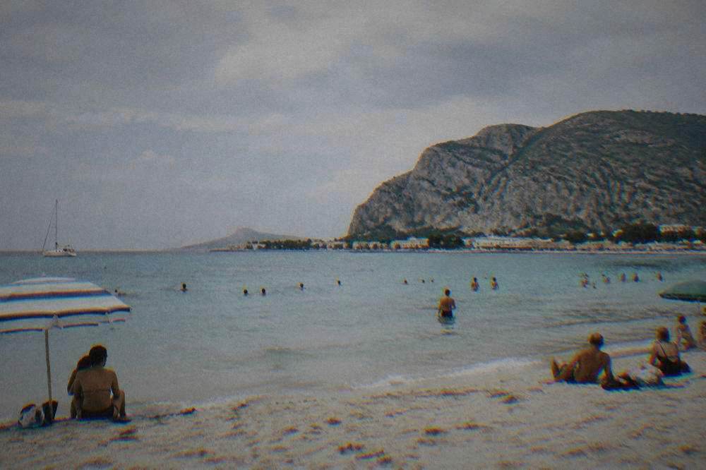 People swimming and relaxing on a sandy beach near Palermo in summer