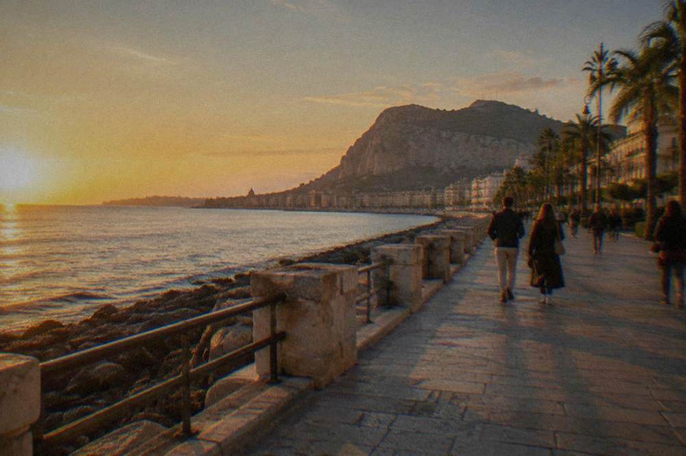 People strolling along the Foro Italico seafront promenade in Palermo at golden hour