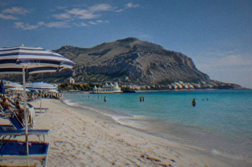 Pale sandy beach at Mondello with turquoise water and a row of umbrellas