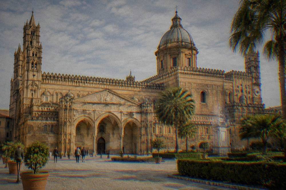 A golden cathedral facade in Palermo seen from a sunlit square