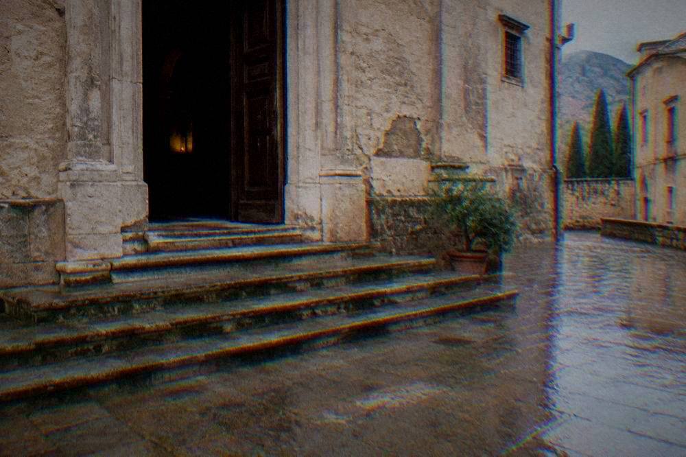 Wet stone steps and a plain doorway of a monastery building on a rainy grey day