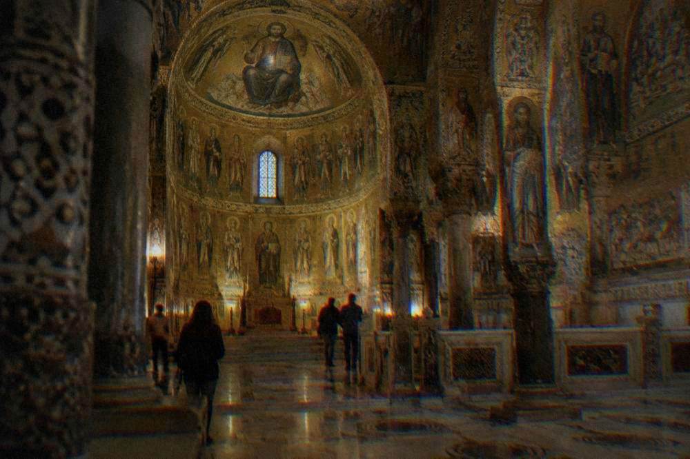 Inside a small royal chapel with a domed ceiling and walls covered in gold mosaics above a marble floor
