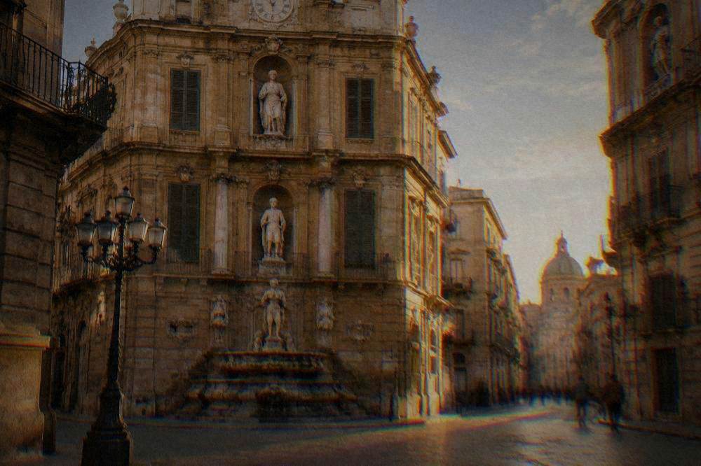 A curved Baroque corner facade of golden limestone with a fountain and tiered statue niches