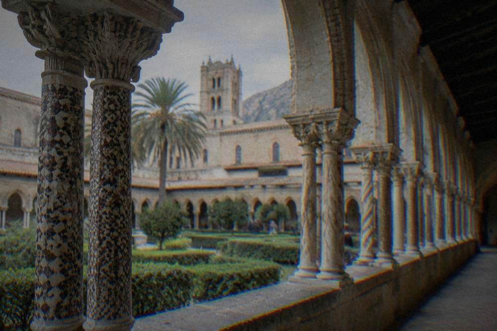 A stone cloister arcade with paired columns and inlaid decoration at Monreale