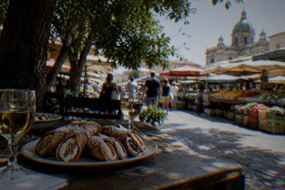 A table with fresh cannoli and small glasses of Sicilian wine