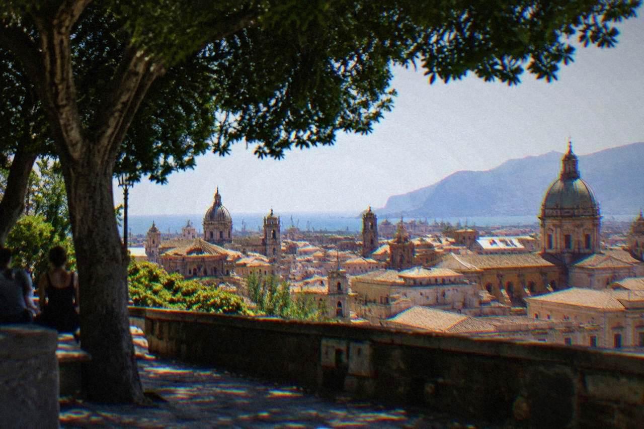 Palermo rooftops and church domes seen from above under a bright sky