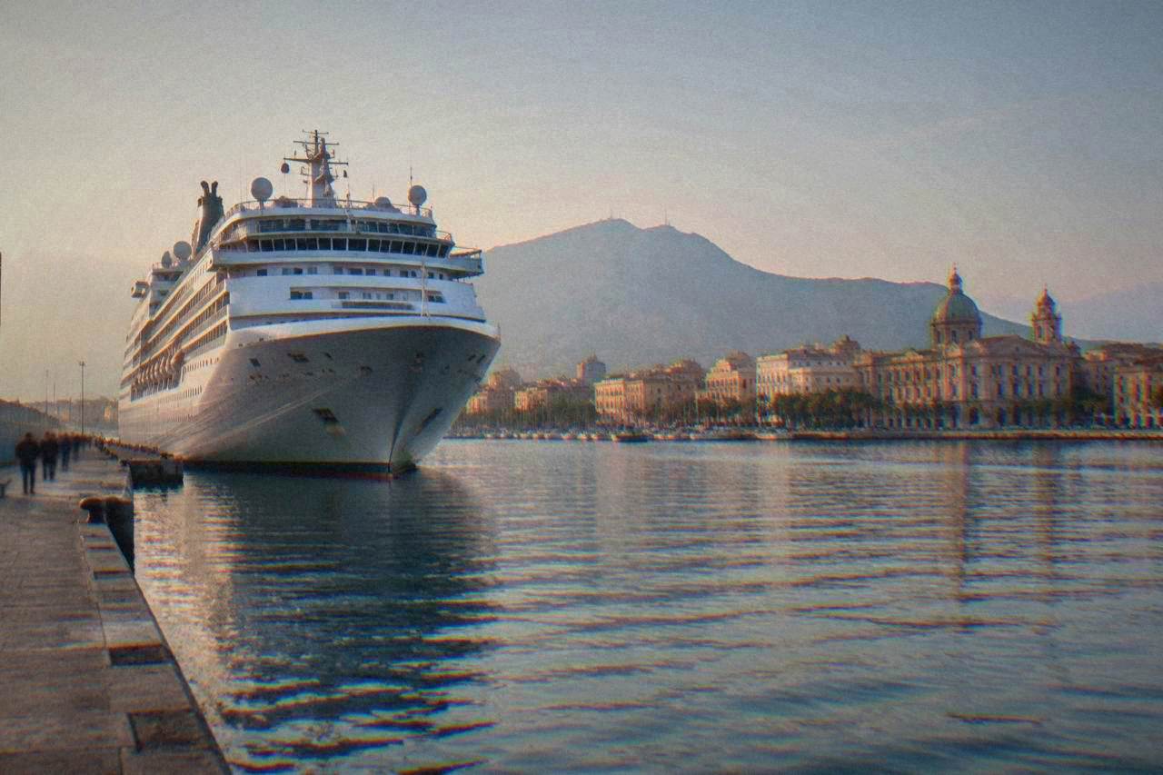 Cruise ship docked at the Palermo waterfront with historic buildings along the shore