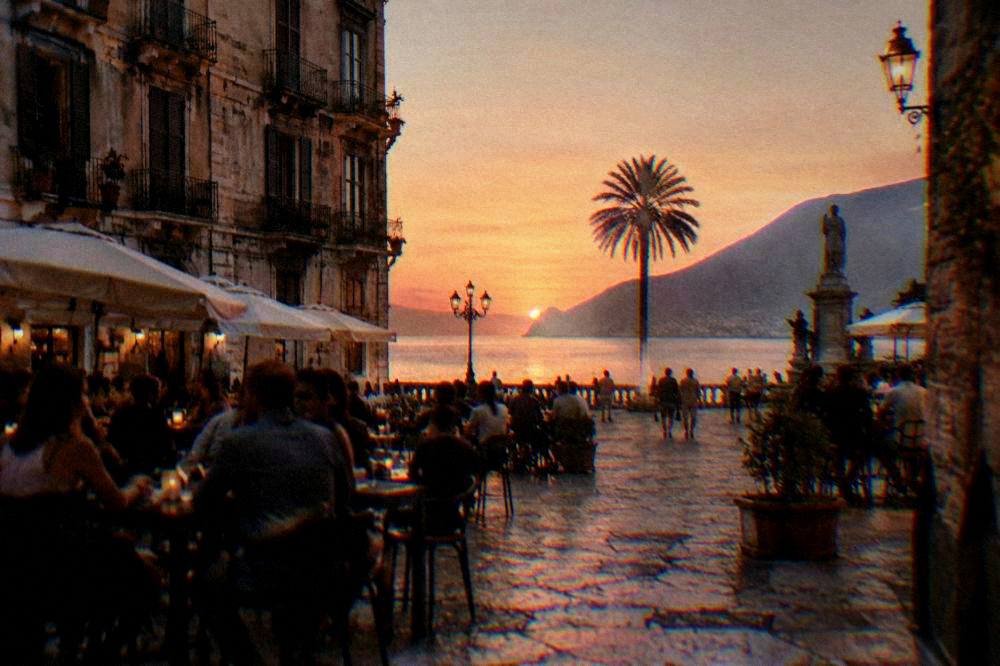 Evening street scene with people at open-air bars in an old Palermo square