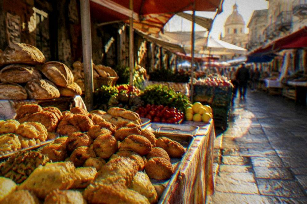 A colourful market street stall with fried snacks, bread and fresh produce in Palermo