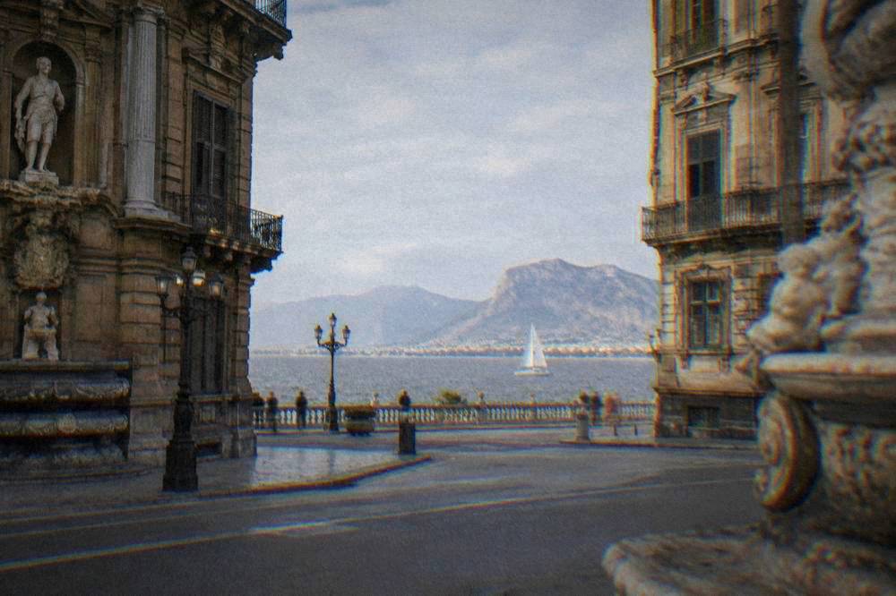 Catamaran sailing on the grey Gulf of Palermo with the coastline in the distance