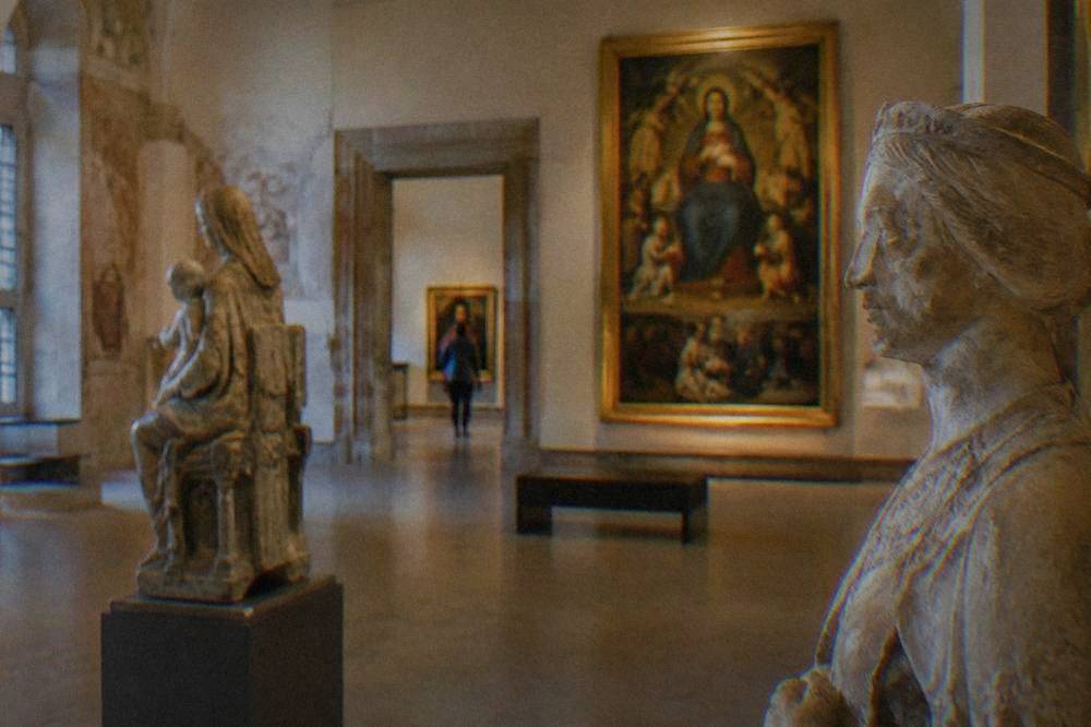 Interior of a Palermo museum gallery with sculptures and paintings under warm lighting
