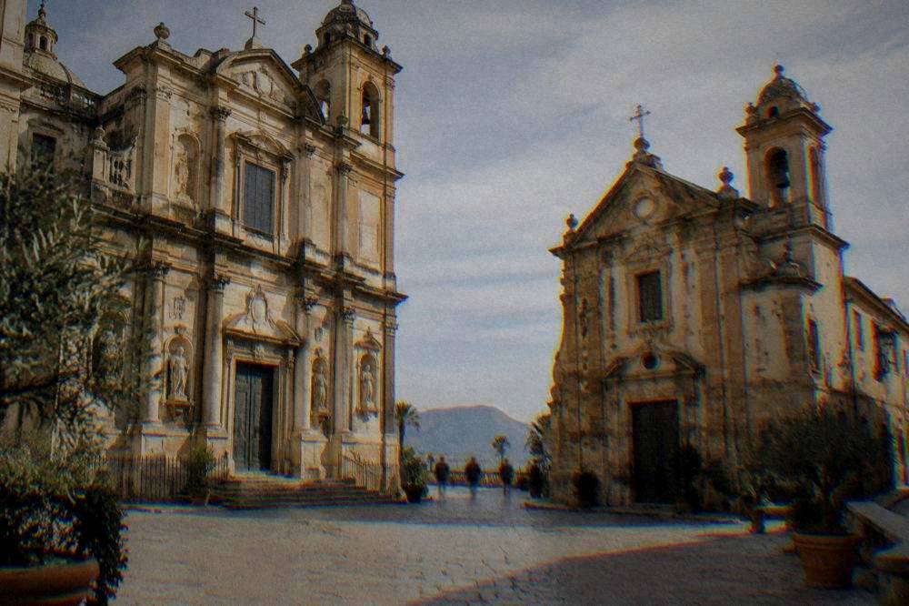 Two adjoining churches of different sizes facing each other across a small stone square